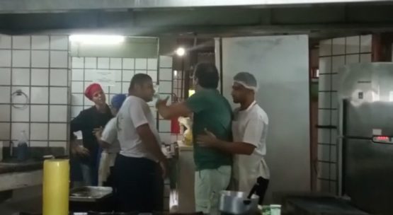 Homem (camisa verde) na cozinha tentando agredir mulher 